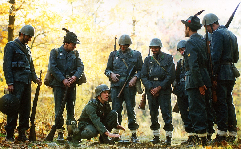 Italian soldiers gathered around a German soldier in the autumn woods